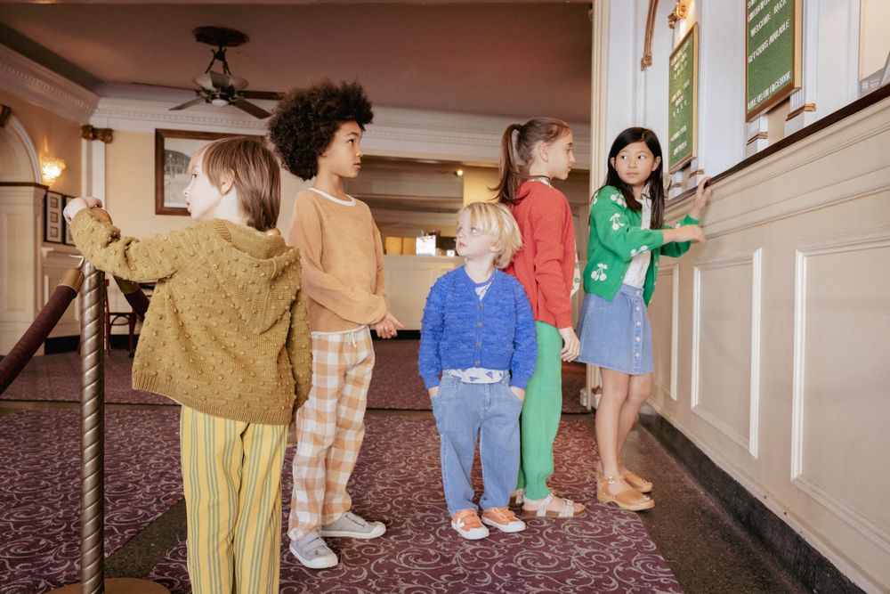Group of children standing in a classic movie theater lobby looking at the board.