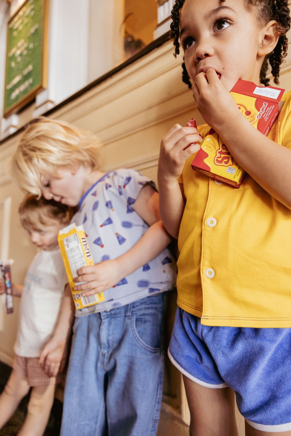 Children eating candy snacks in a colorful movie theater concession area.