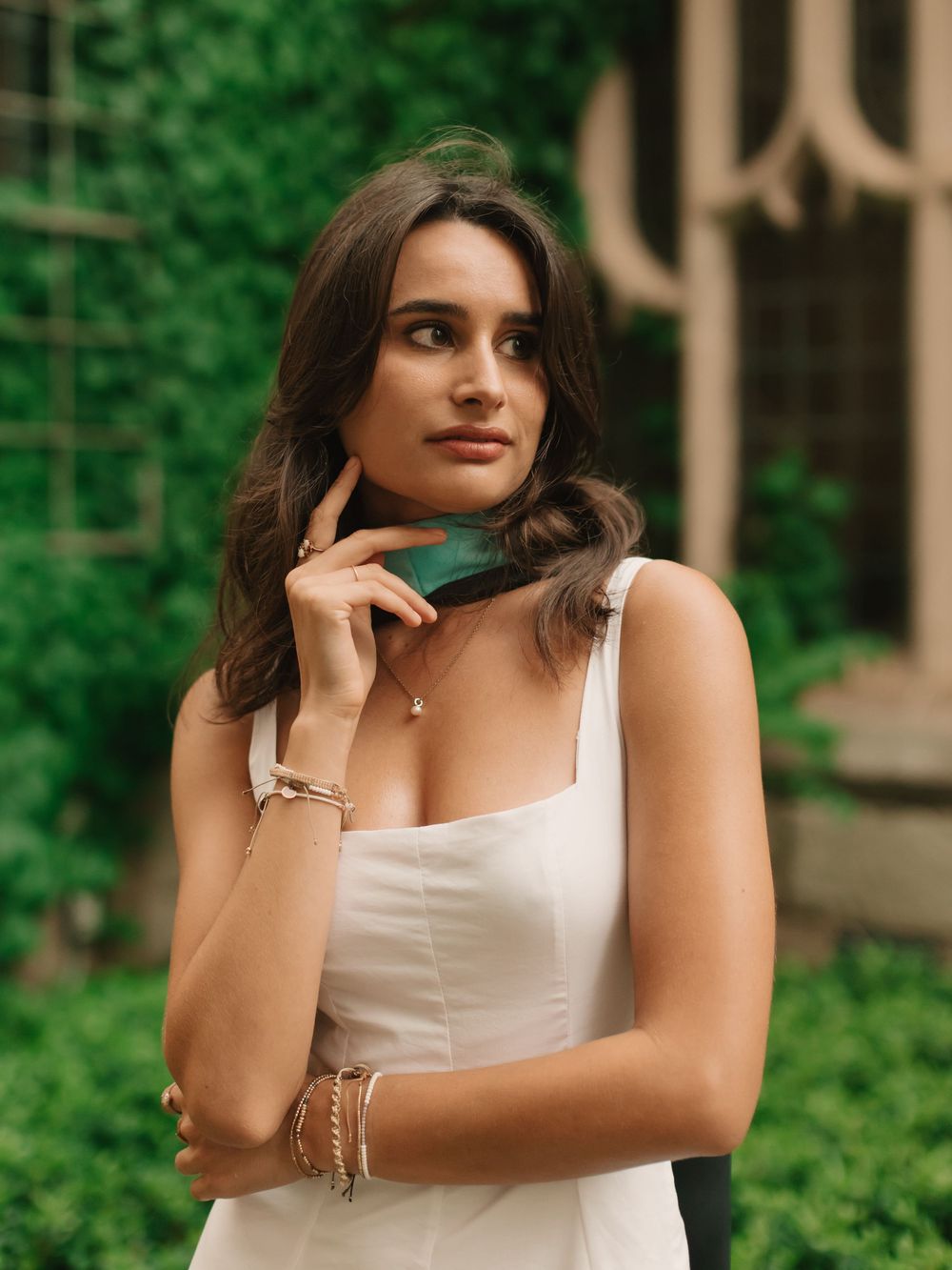 Boston college graduate looking away from camera near an ivy wall on campus