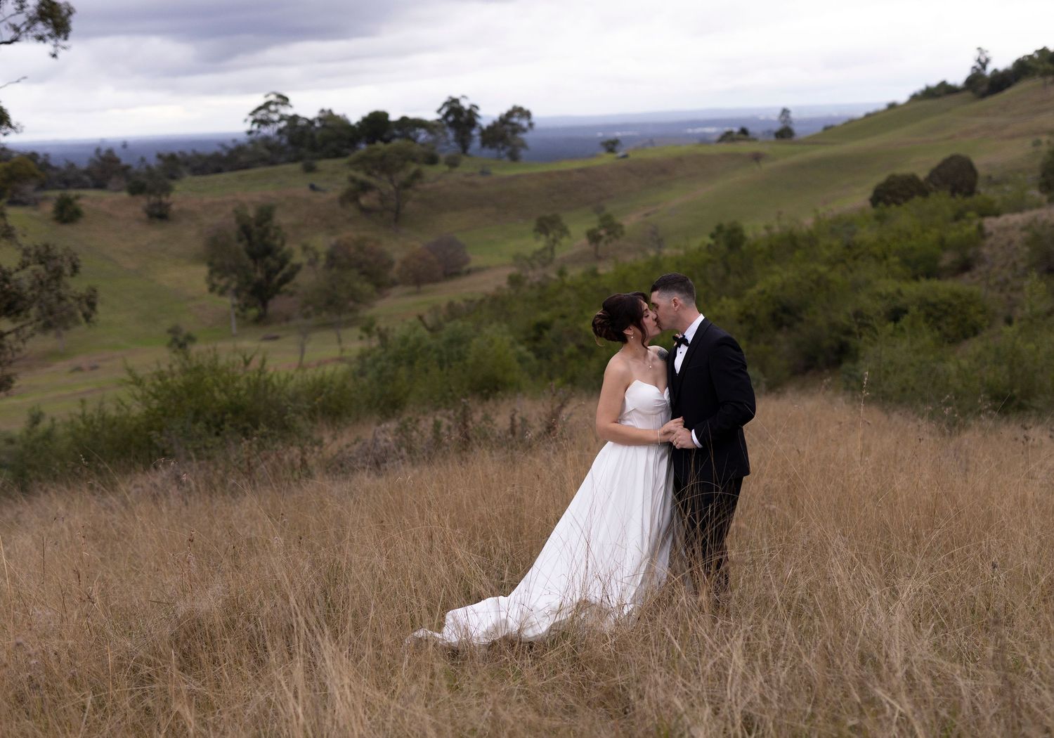 Black and white photo of a bride and groom sharing a romantic kiss, with the brides veil flowing around them.