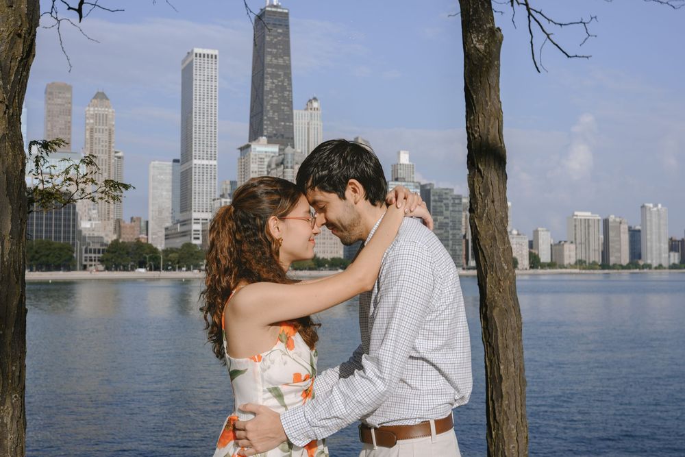 Couple embracing romantically by a lakeside with Chicago skyline skyscrapers in the background on a sunny day.
