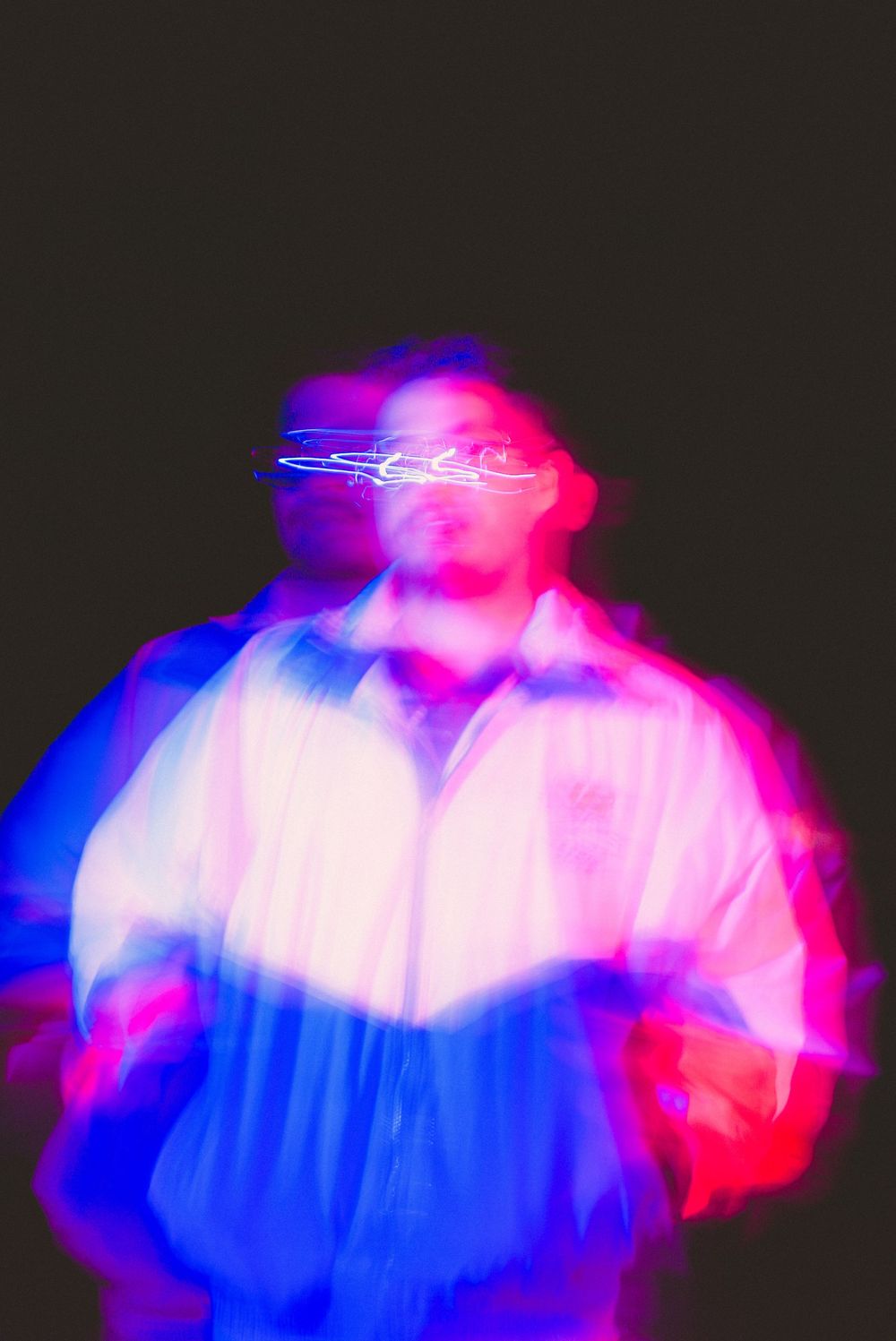 Abstract motion blur portrait of a man in a white jacket with red and blue light effects against dark background.