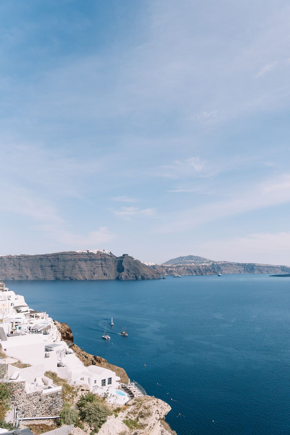 Stunning aerial view of Santorini caldera with white buildings on cliffs overlooking deep blue Aegean Sea, Greece.