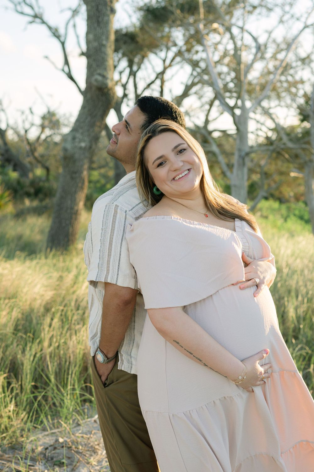 Expectant parents sharing a quiet moment beneath the trees during their maternity photo session.