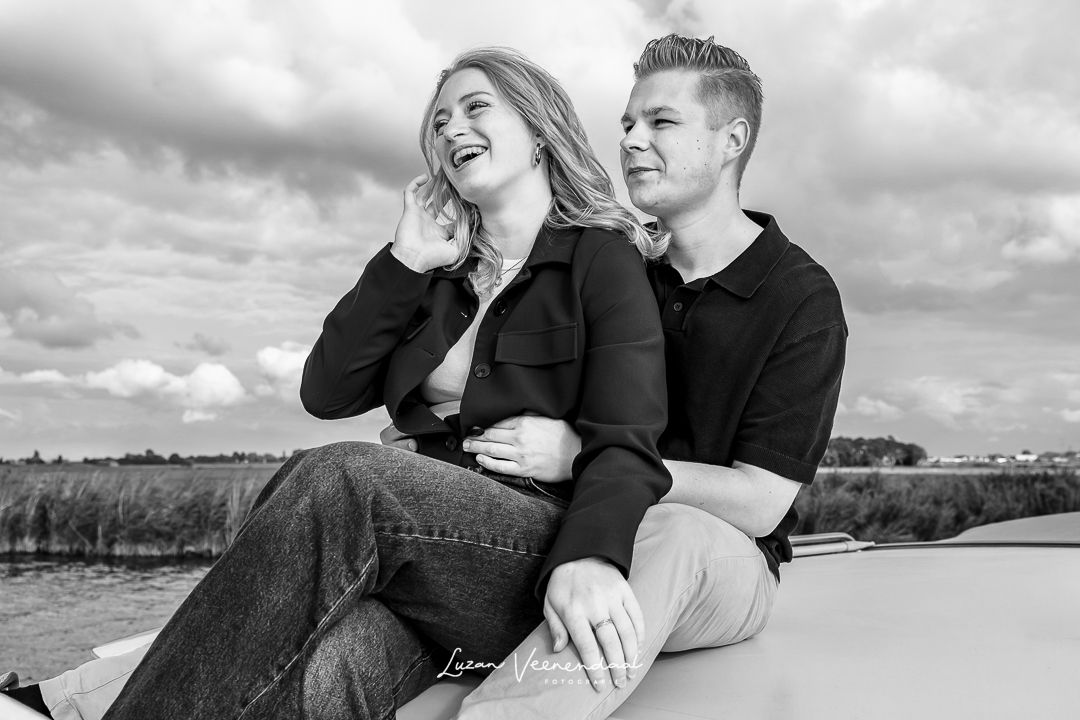 Zwart-witfoto van dochter die voor haar vriend zit tijdens een familiefotoshoot op de boot op het Uitgeestermeer