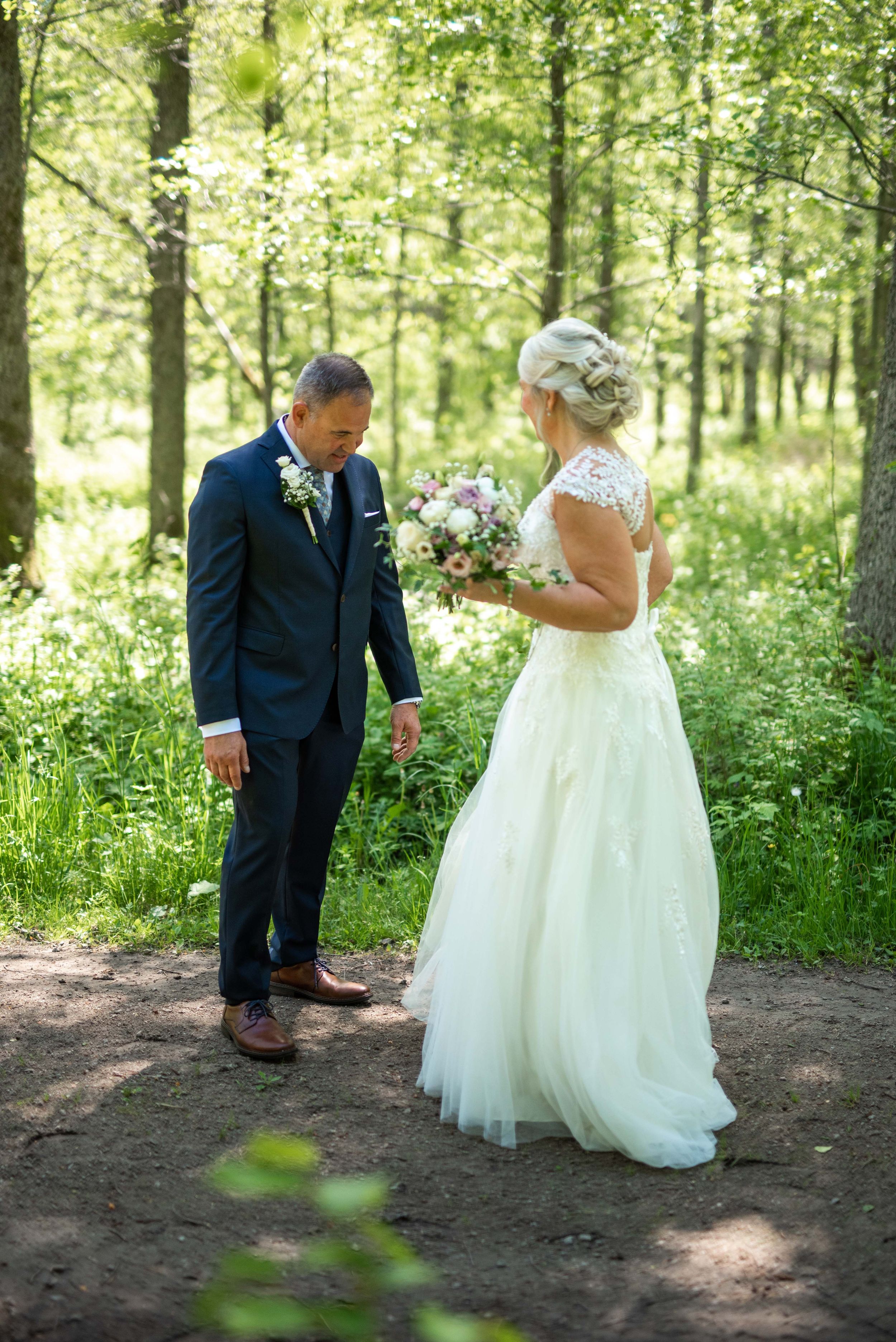 Brudpar som har sin first look där mannen kollar på brudens klänning.