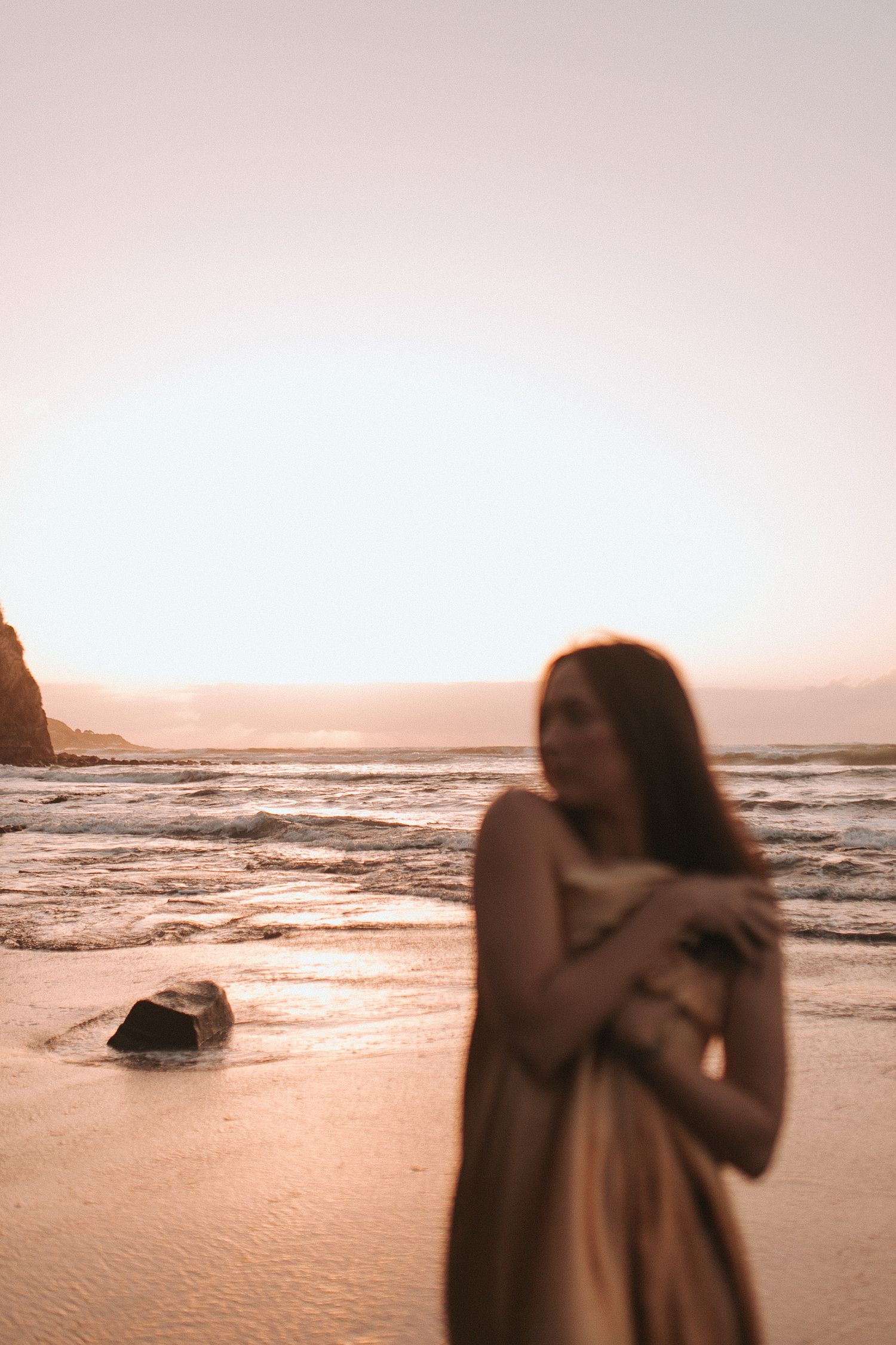 Woman draped in gold fabric on Raglan's black sand beach at sunset — Goddess Shoot® by Nami Creative
