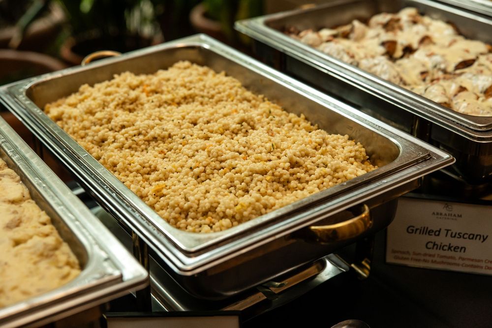 Buffet trays of golden rice pilaf and grilled Tuscany chicken served in stainless steel chafing dishes.