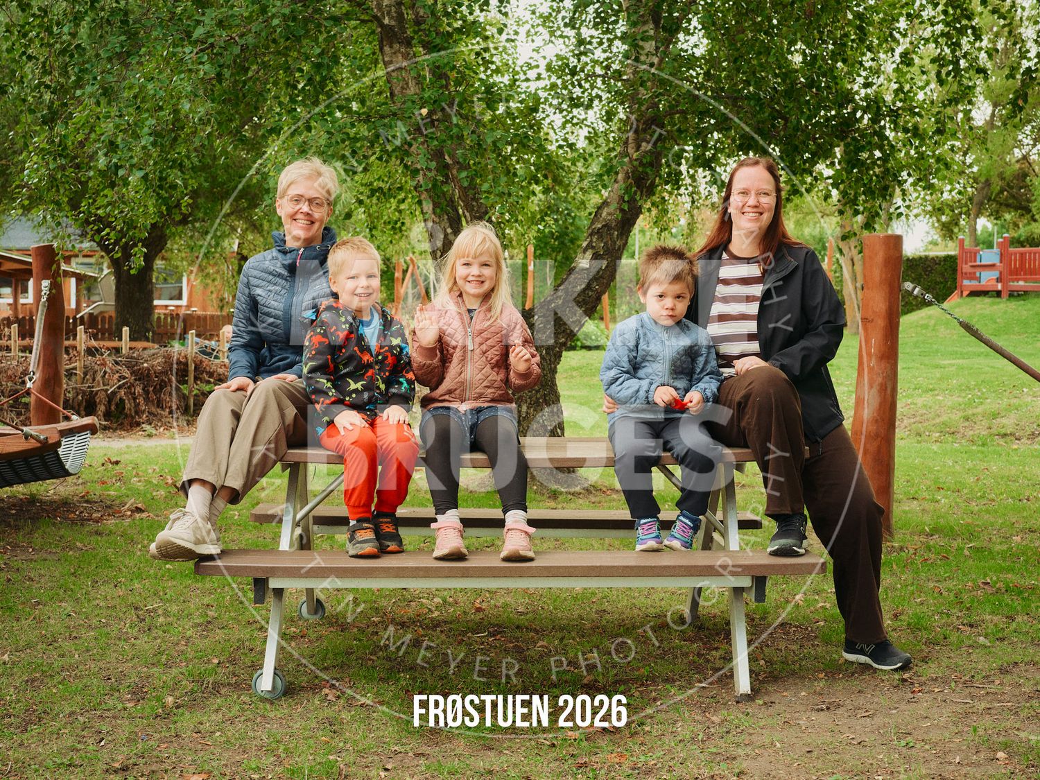Family of five posing on a wooden bench outdoors under trees, with text Frostuen 2026 overlay.
