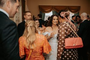 Bride in white strapless gown mingles with wedding guests in colorful attire at elegant indoor reception.