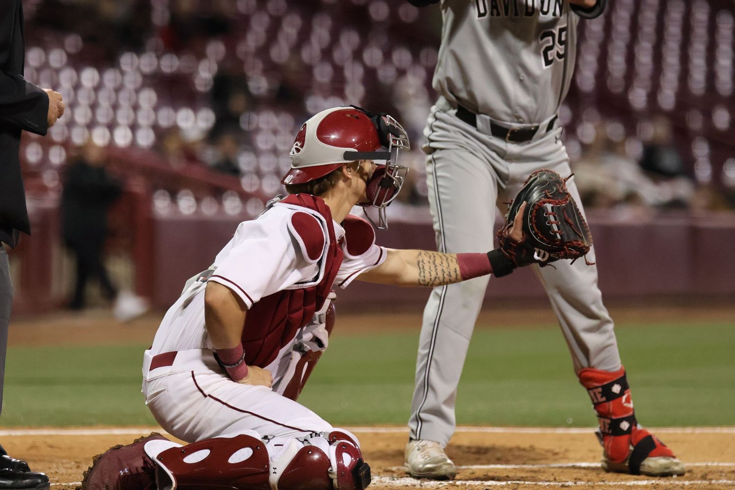 South Carolina catcher reaches his glove toward the plate beside a batter.