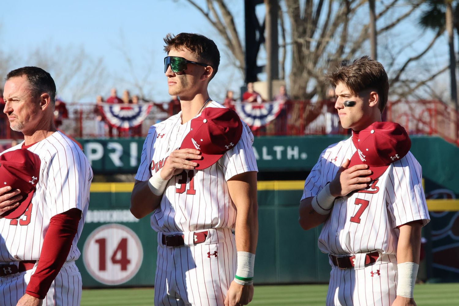 South Carolina baseball players hold their caps over their hearts before a game.