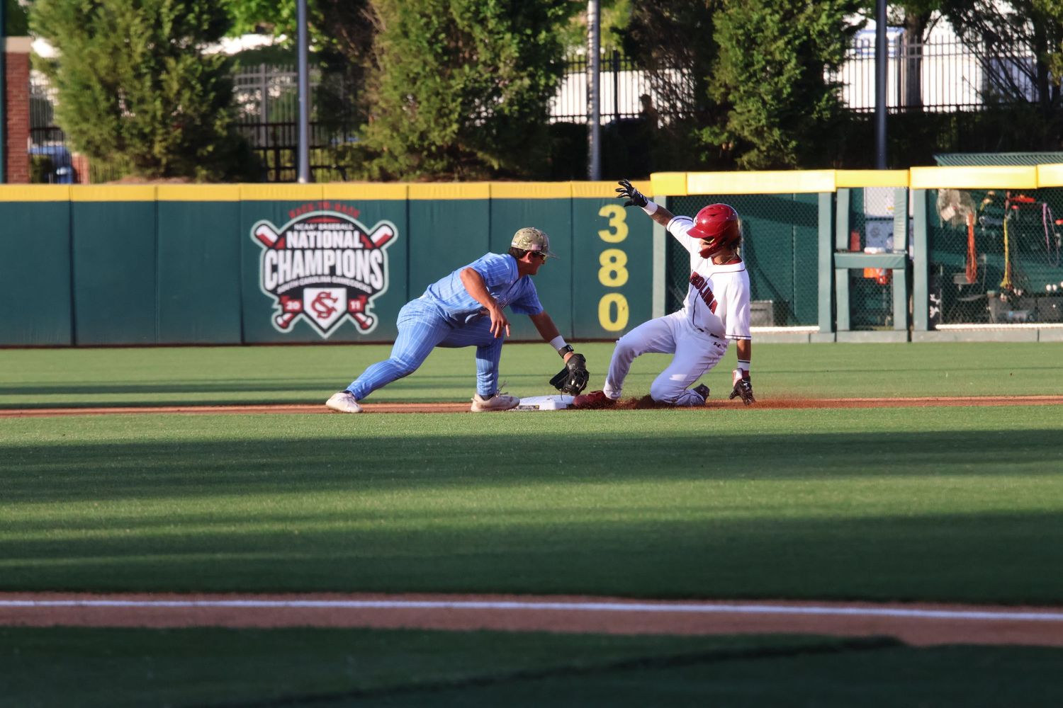 Baseball runner slides into second base as an infielder applies a tag.