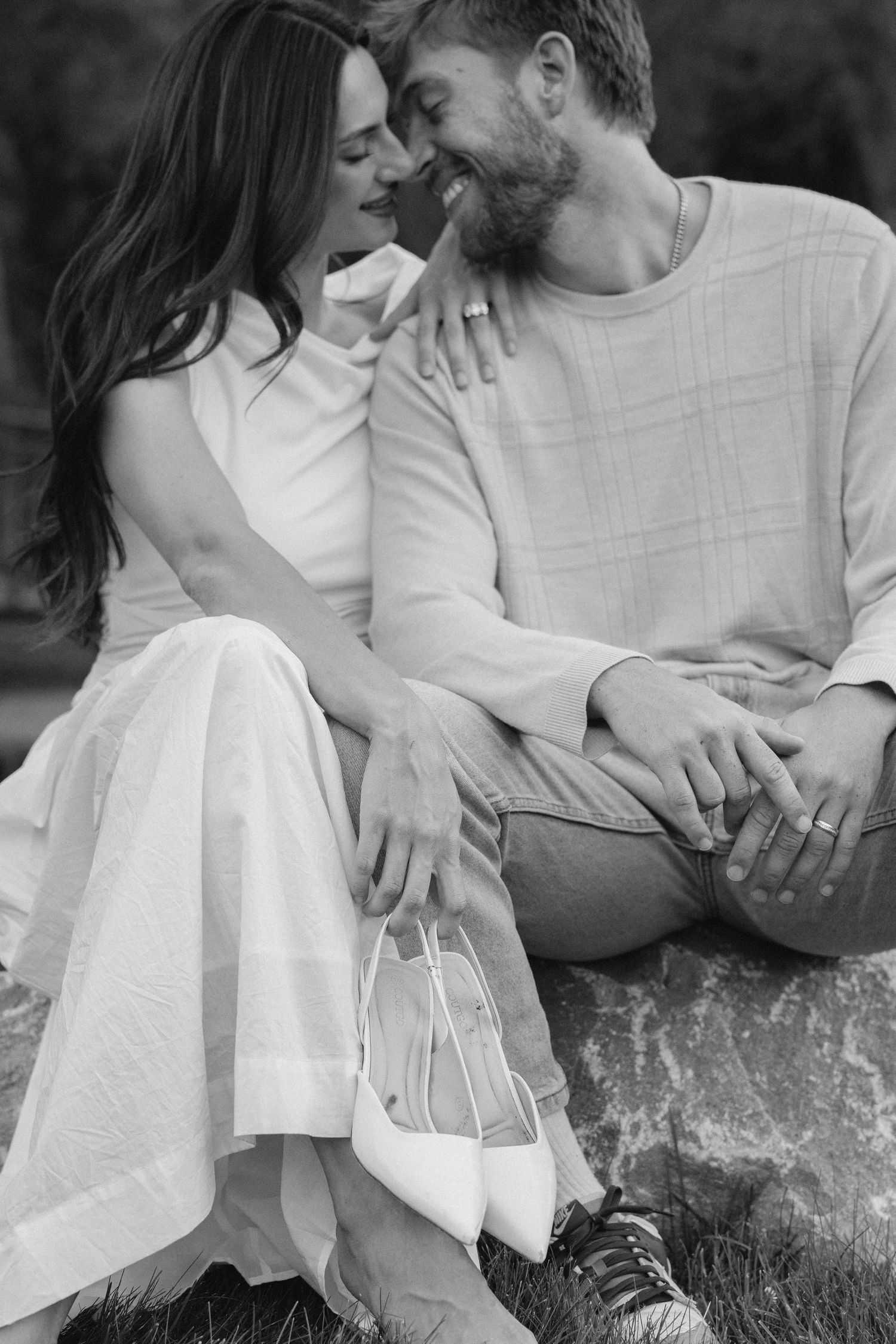 Two people embrace in white outfits while standing on red rock formations in a desert canyon landscape.