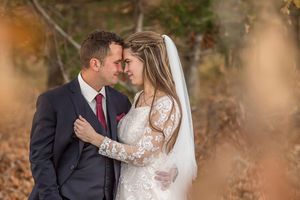 Bride and groom share an intimate moment surrounded by golden autumn leaves in fall wedding portrait.