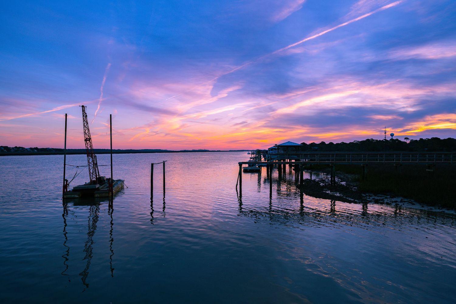 Beautiful sunset panorama over a coastal dock with pink and purple sky.