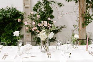 Minimalist wedding table setting with delicate floral arrangements in glass vases.