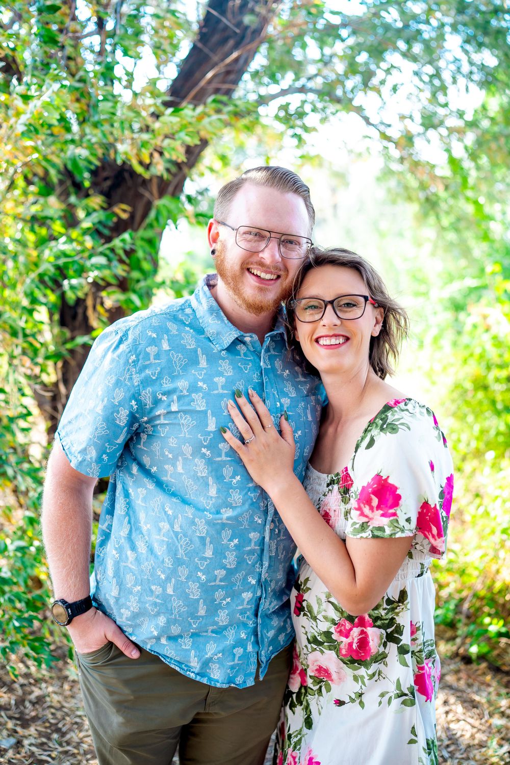 Couple in coordinating blue and floral outfits pose together on a nature path.