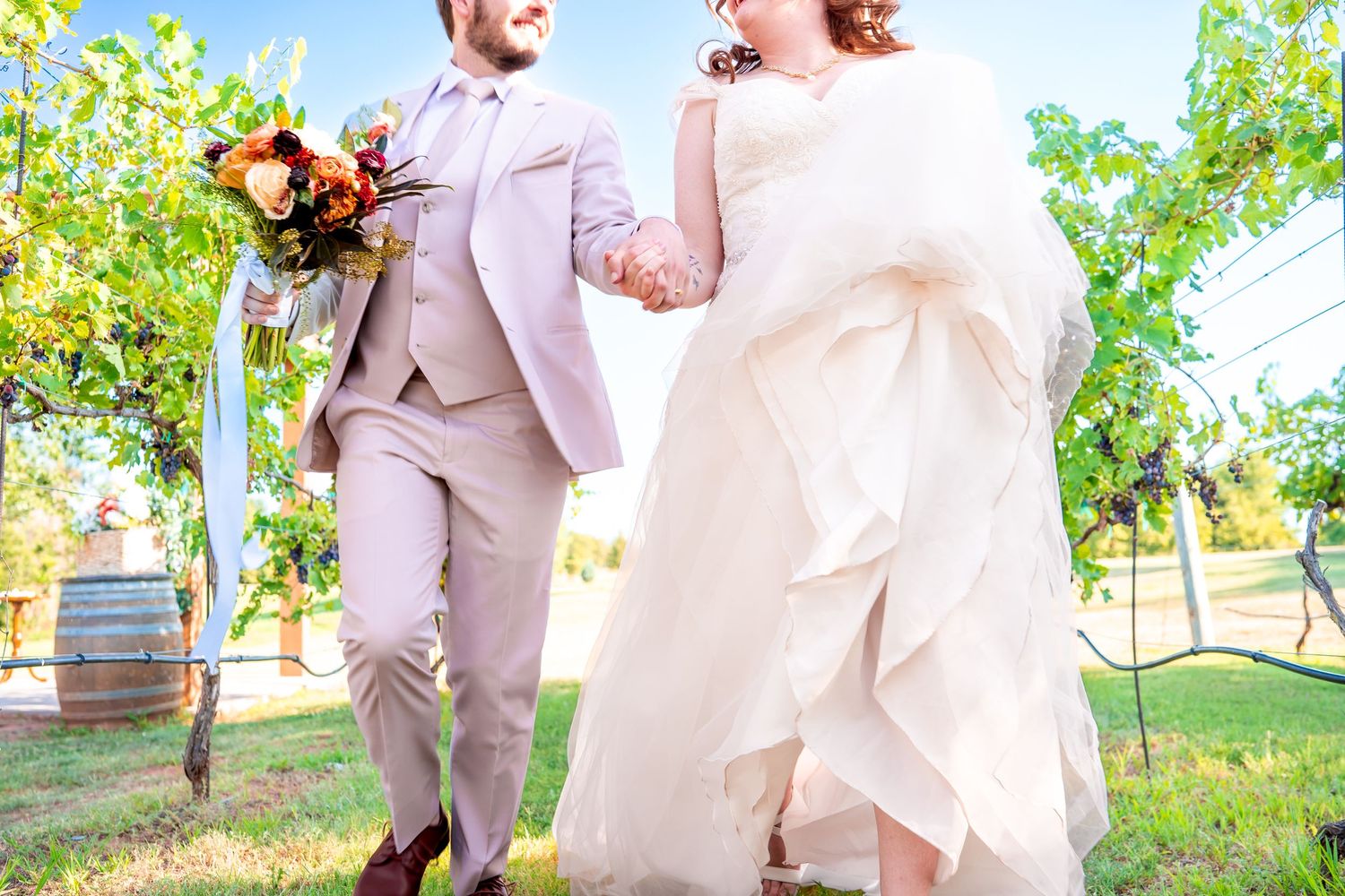 Wedding couple laughing together outdoors, with the groom in light beige suit.