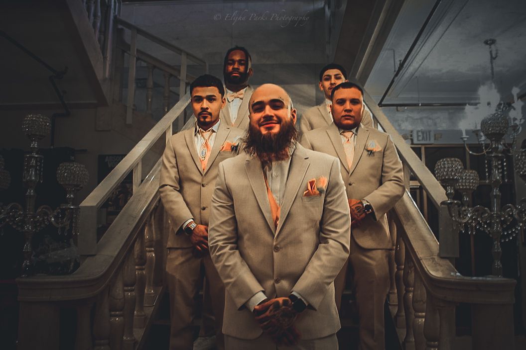 The groom is standing in front of four staggered groomsmen.  They are standing on a stairwell in wedding attire.