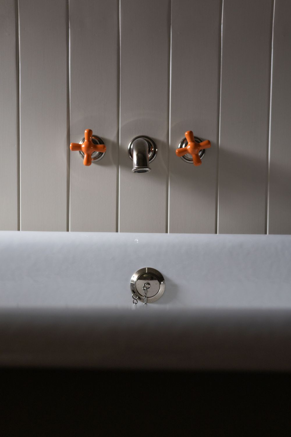 Close-up of modern bathroom fixtures against white paneled wall.
