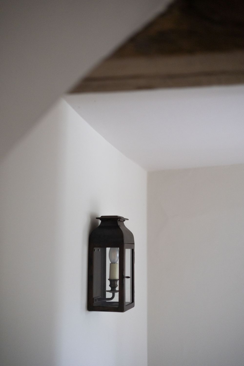 Geometric black lantern mounted on clean white interior wall.