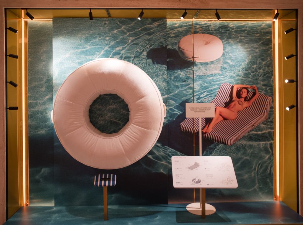 Modern lounge area featuring pink circular seating pods and golden accent lighting. Harrods exhibition.