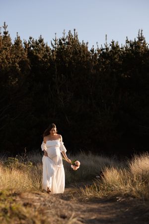 Sunset maternity session, mum walking holding flowers and bump