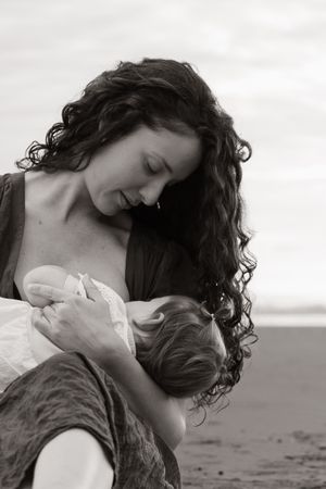 mum nursing her baby on the beach during a sunrise family session at waimari beach, christchurch