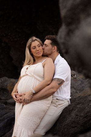maternity sunrise session at sumner beach in christchurch, dad holding onto baby bump
