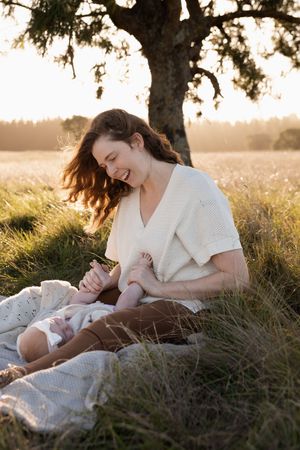 Mum smiling at her baby, holding her feet during motherhood session