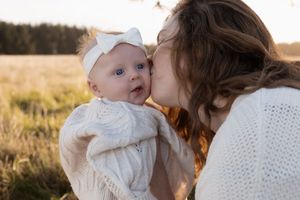 mum kissing her baby during sunset motherhood session at mcleans island, christchurch