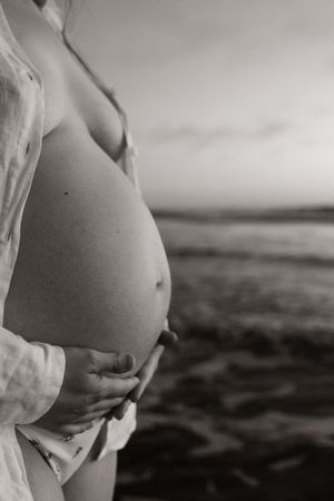 mum to be holding onto bump during sunrise maternity session in christchurch
