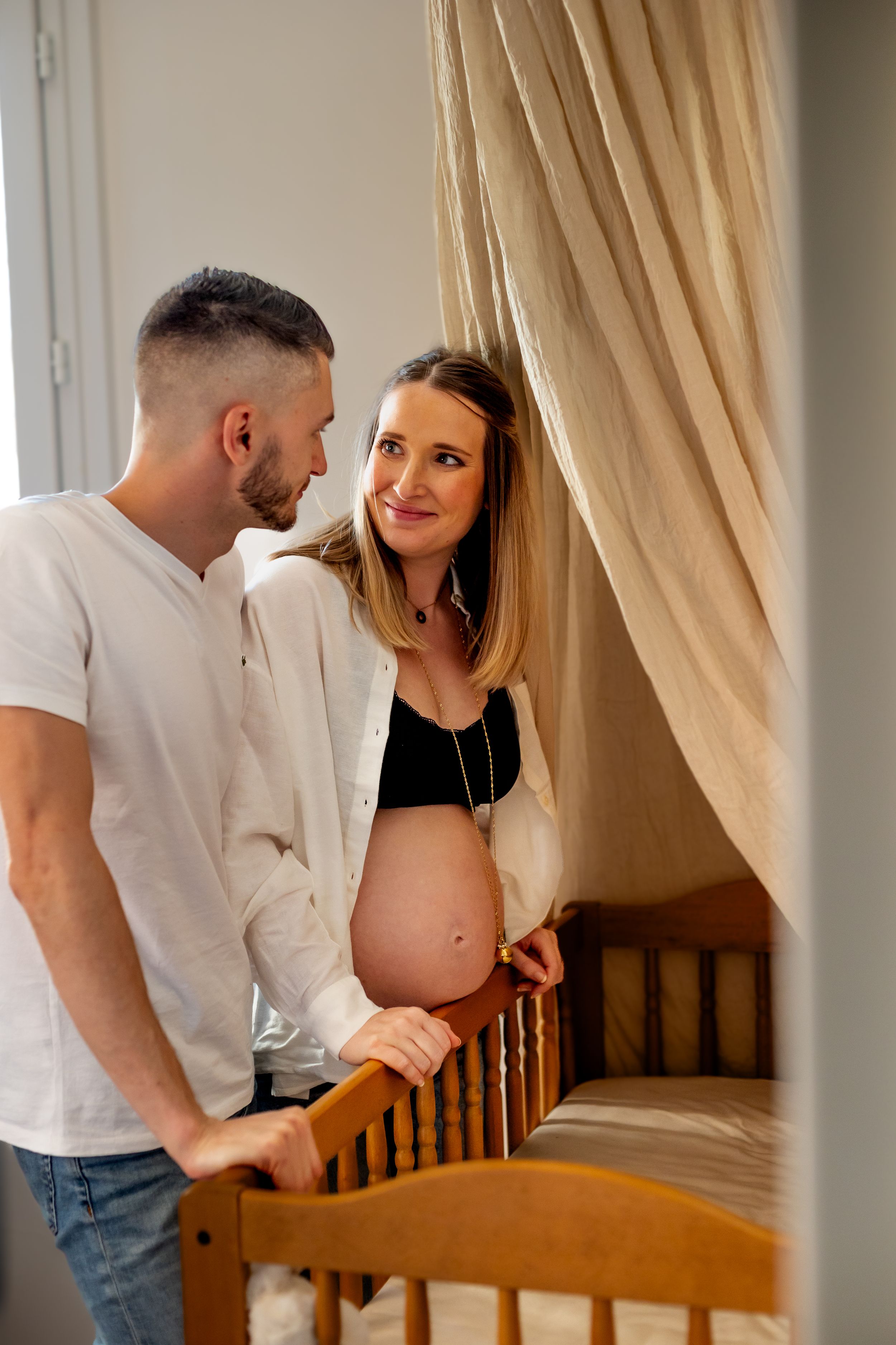 Photo de grossesse à domicile – femme enceinte avec son partenaire au-dessus du berceau