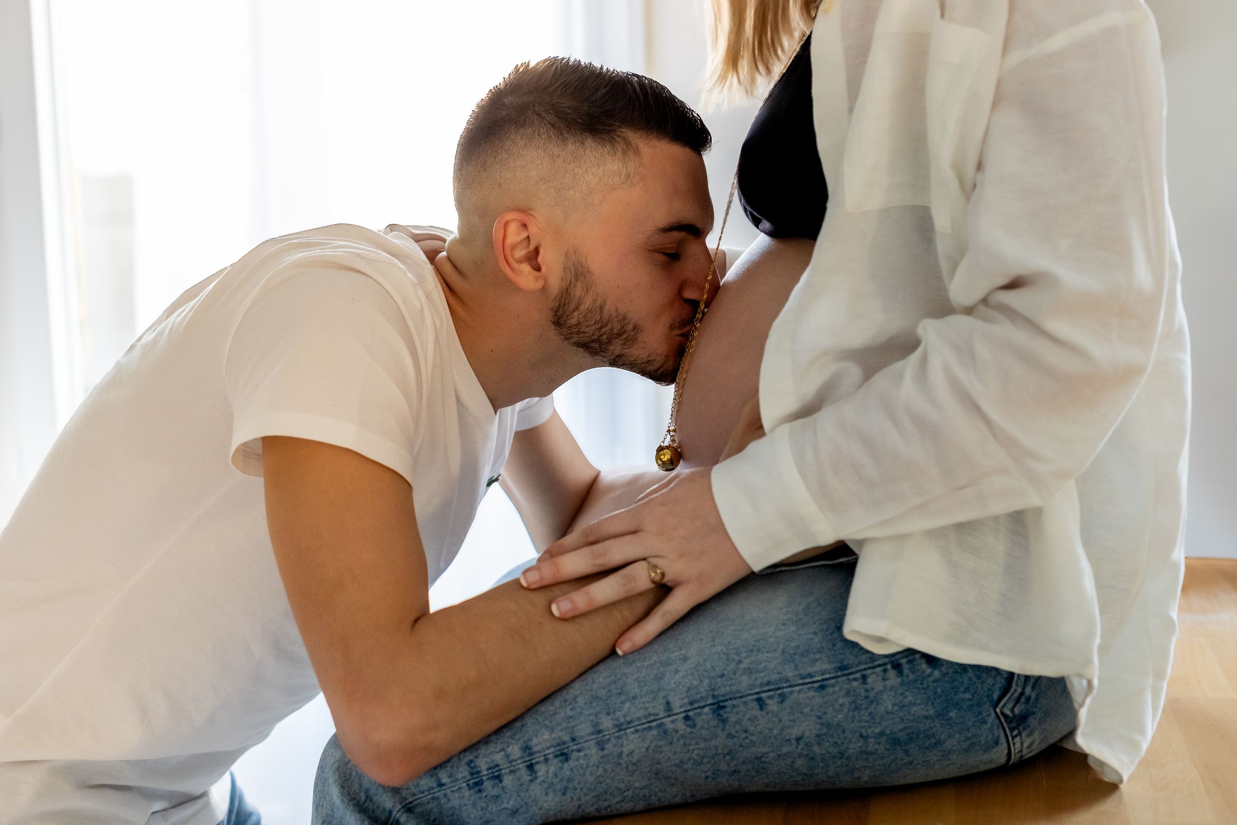 Photo de grossesse lifestyle à domicile – femme enceinte assise sur le canapé avec son partenaire