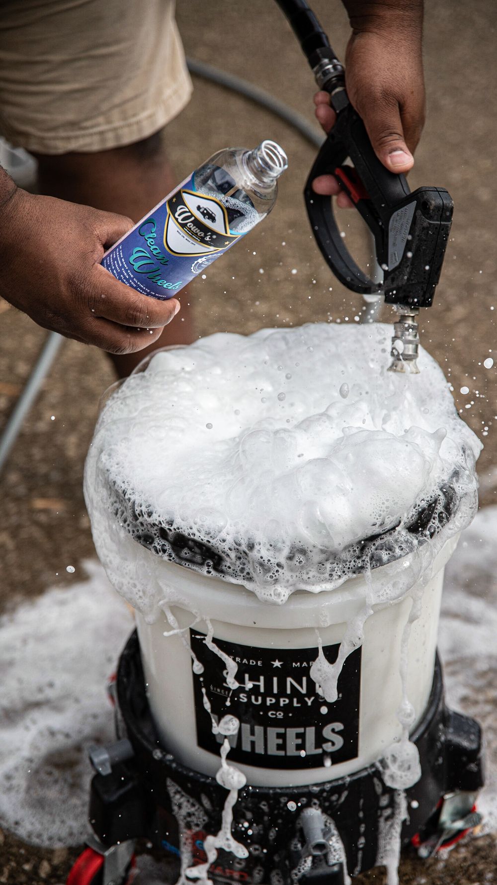 Foaming car wash bucket with cleaning solution and spray nozzle.