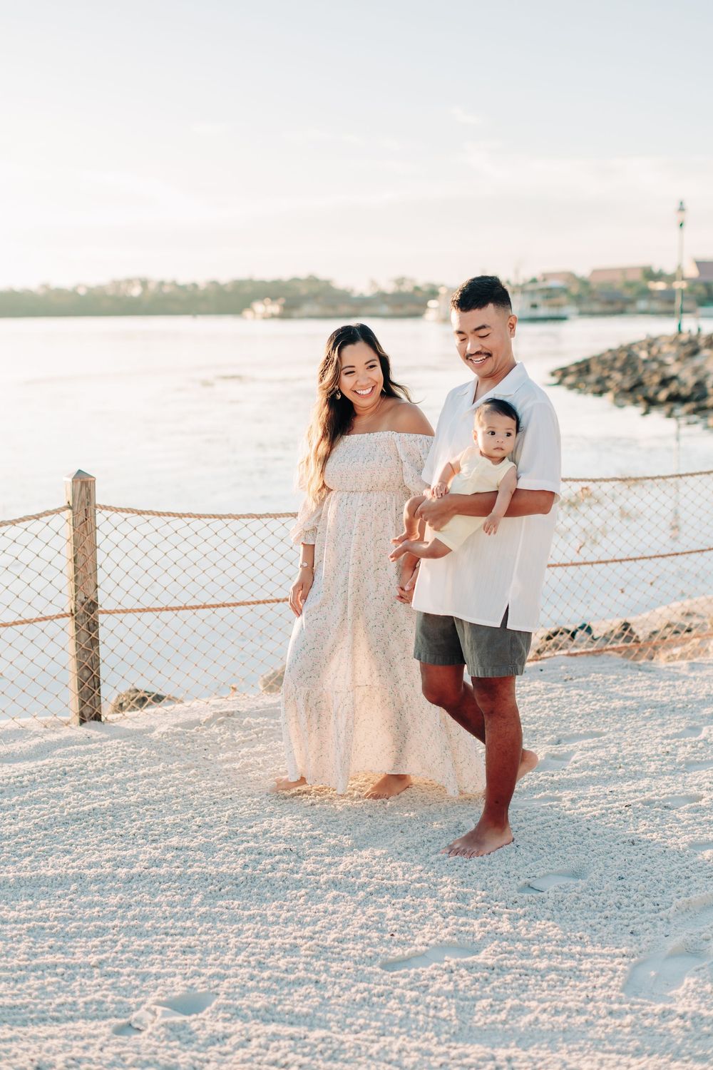 A family walking together along a sandy beach path during morning golden hour.