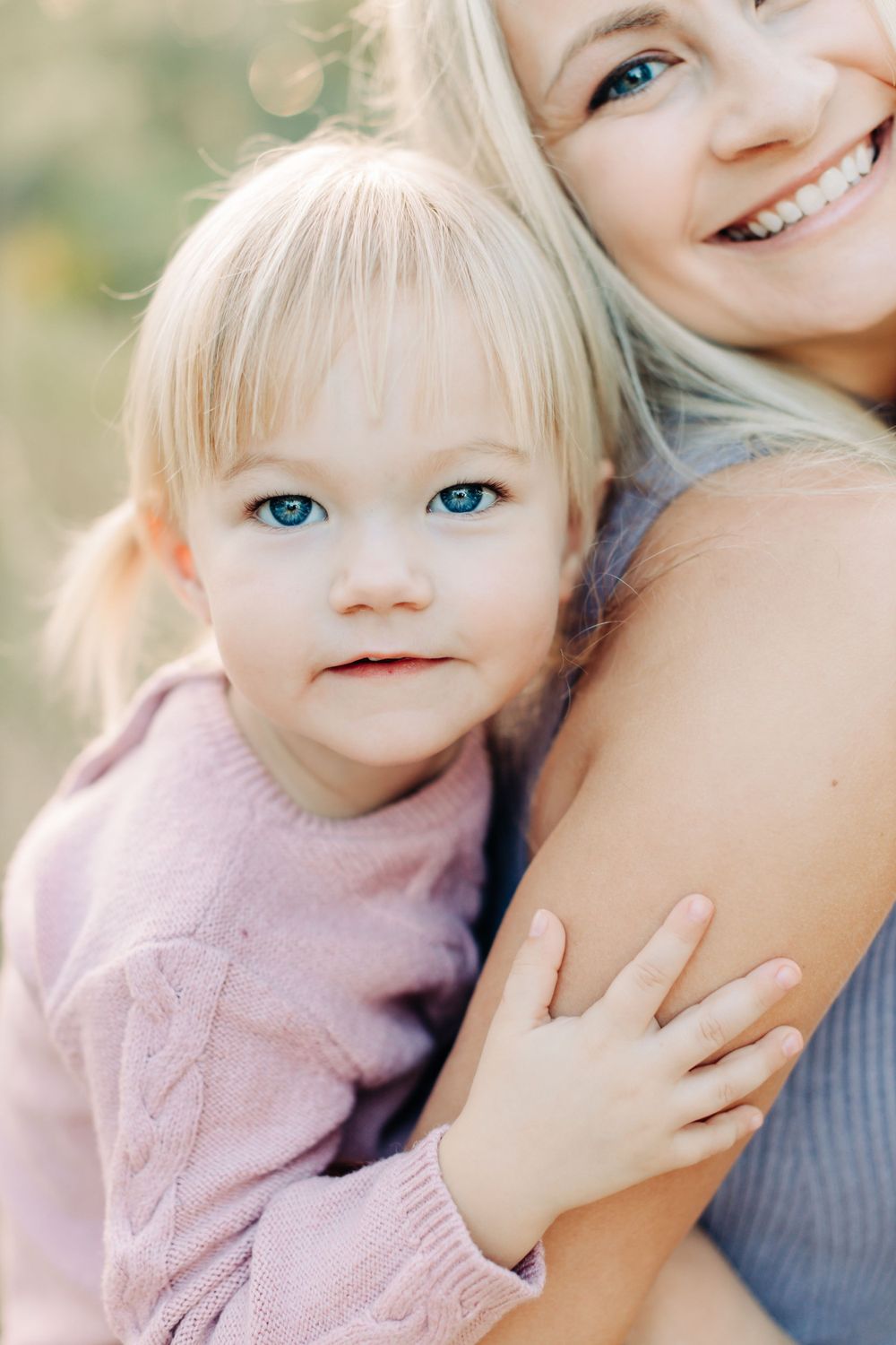 Girl with big blue eyes smiling while piggy back rides her mom during Orlando family photography session.