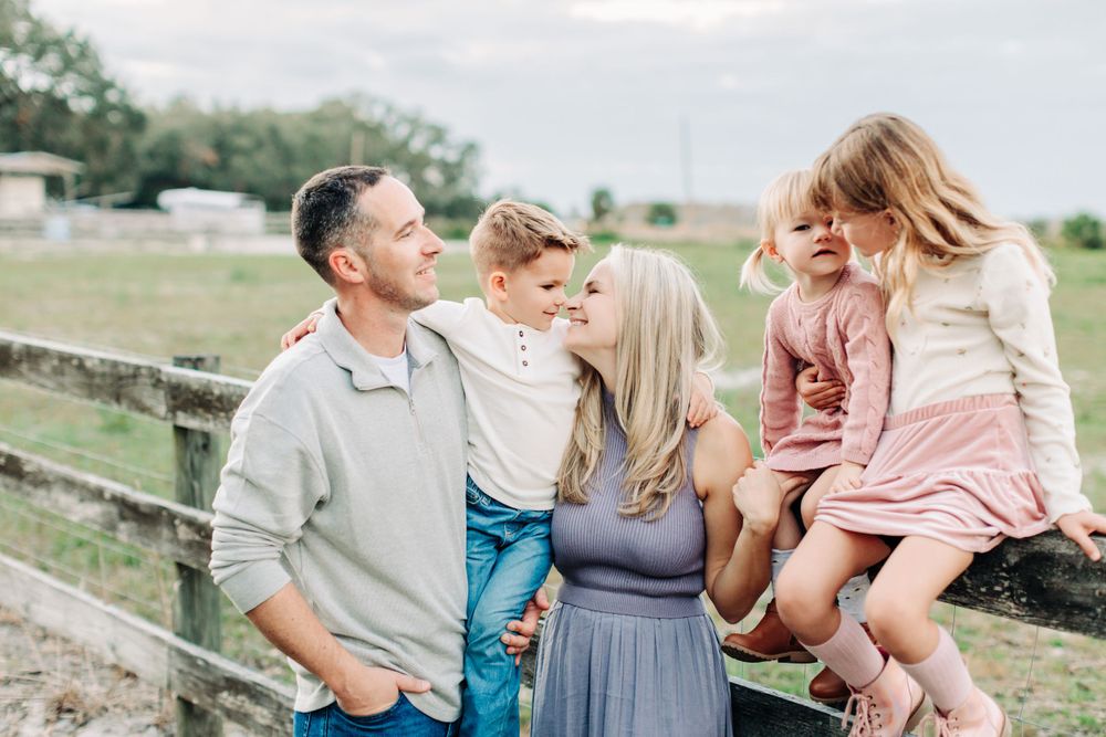 Family playfully sitting on the fence during a lifestyle family photo session in Orlando.
