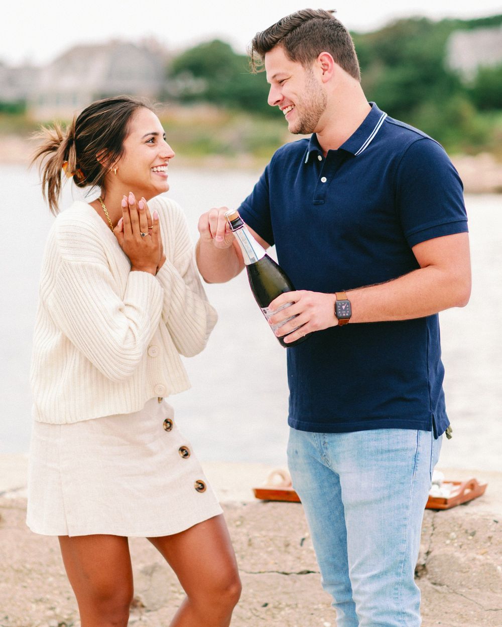 A couple celebrating with champagne on the beach during a proposal moment.