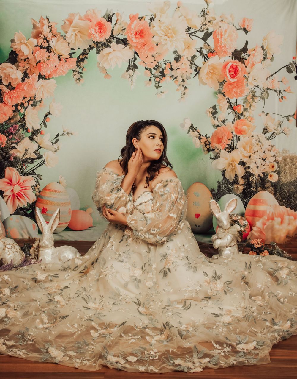 Romantic portrait with peach floral arch backdrop featuring elegant lace gown and dreamy springtime decorations.