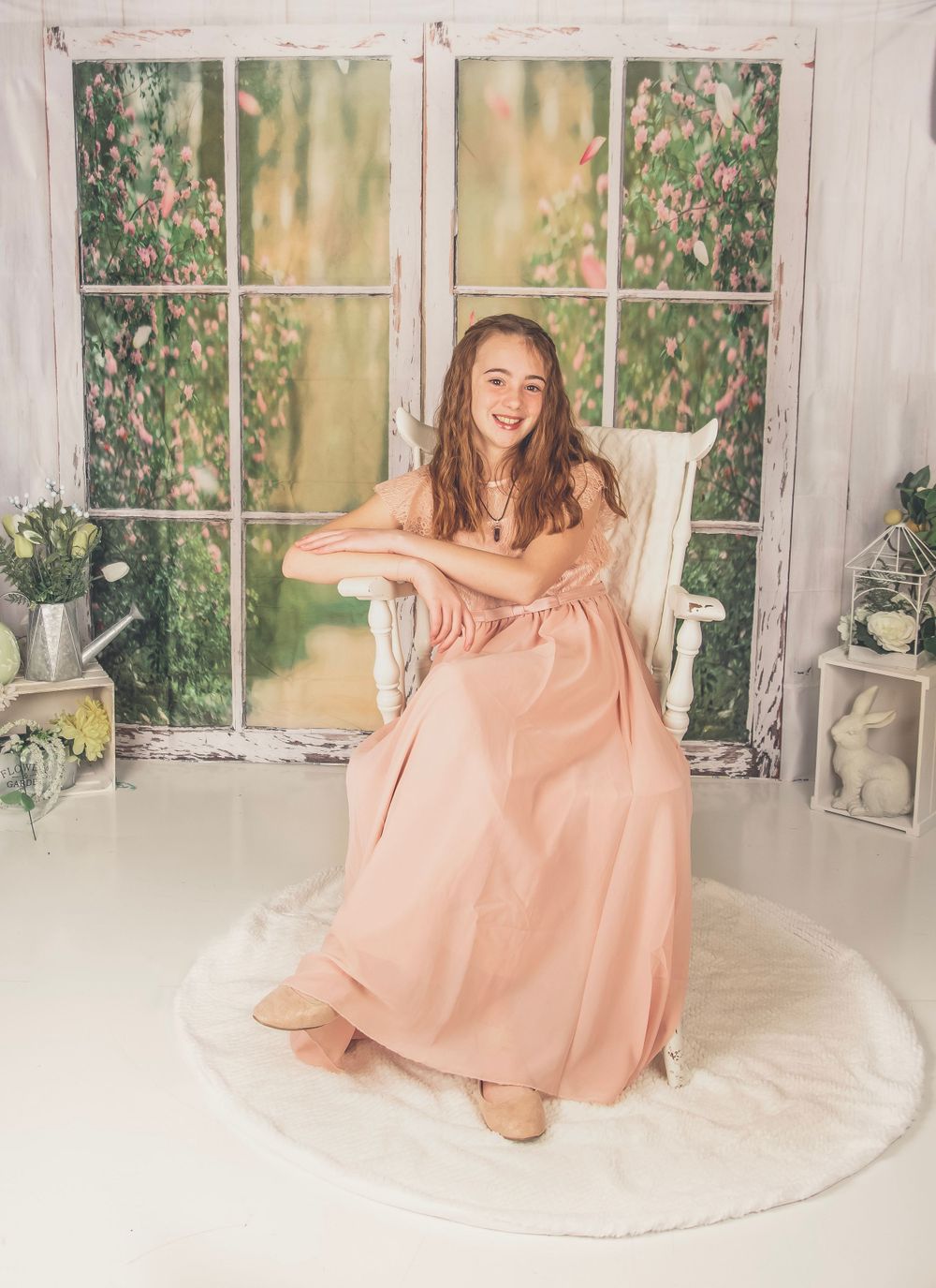 Dreamy indoor scene with pink dress against white window frame and floral garden backdrop.