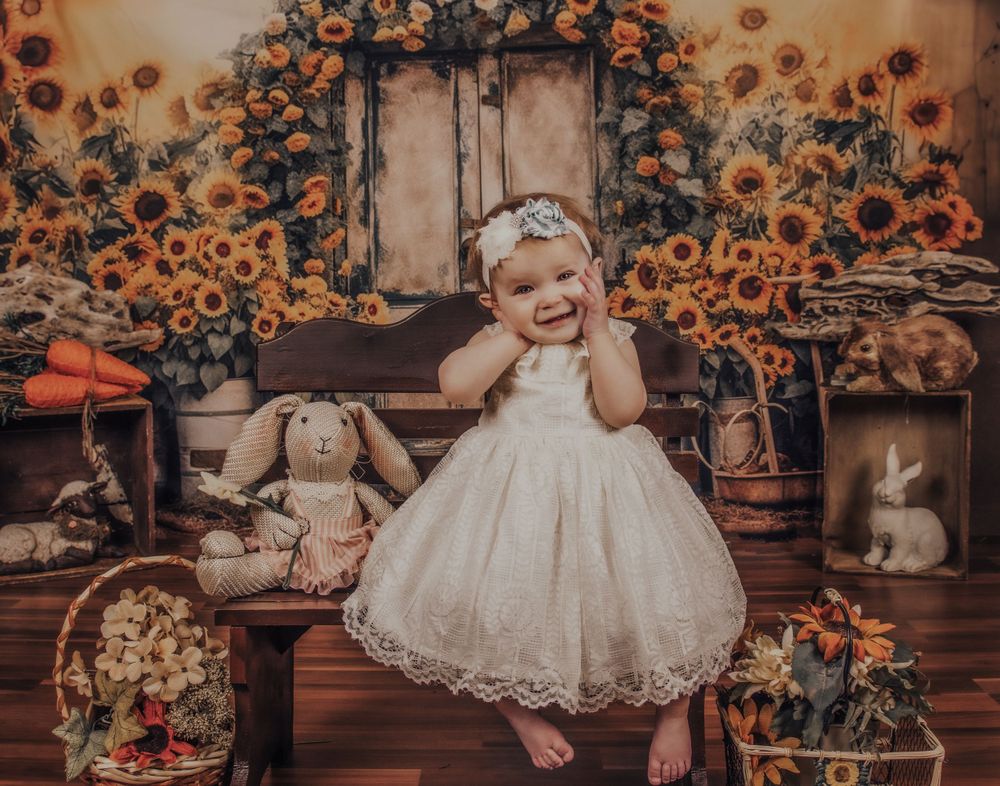 White lace dress against rustic wooden backdrop with vibrant sunflower arch and vintage decor.