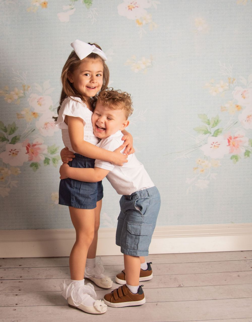 Sweet candid moment showing playful interaction against a floral backdrop.