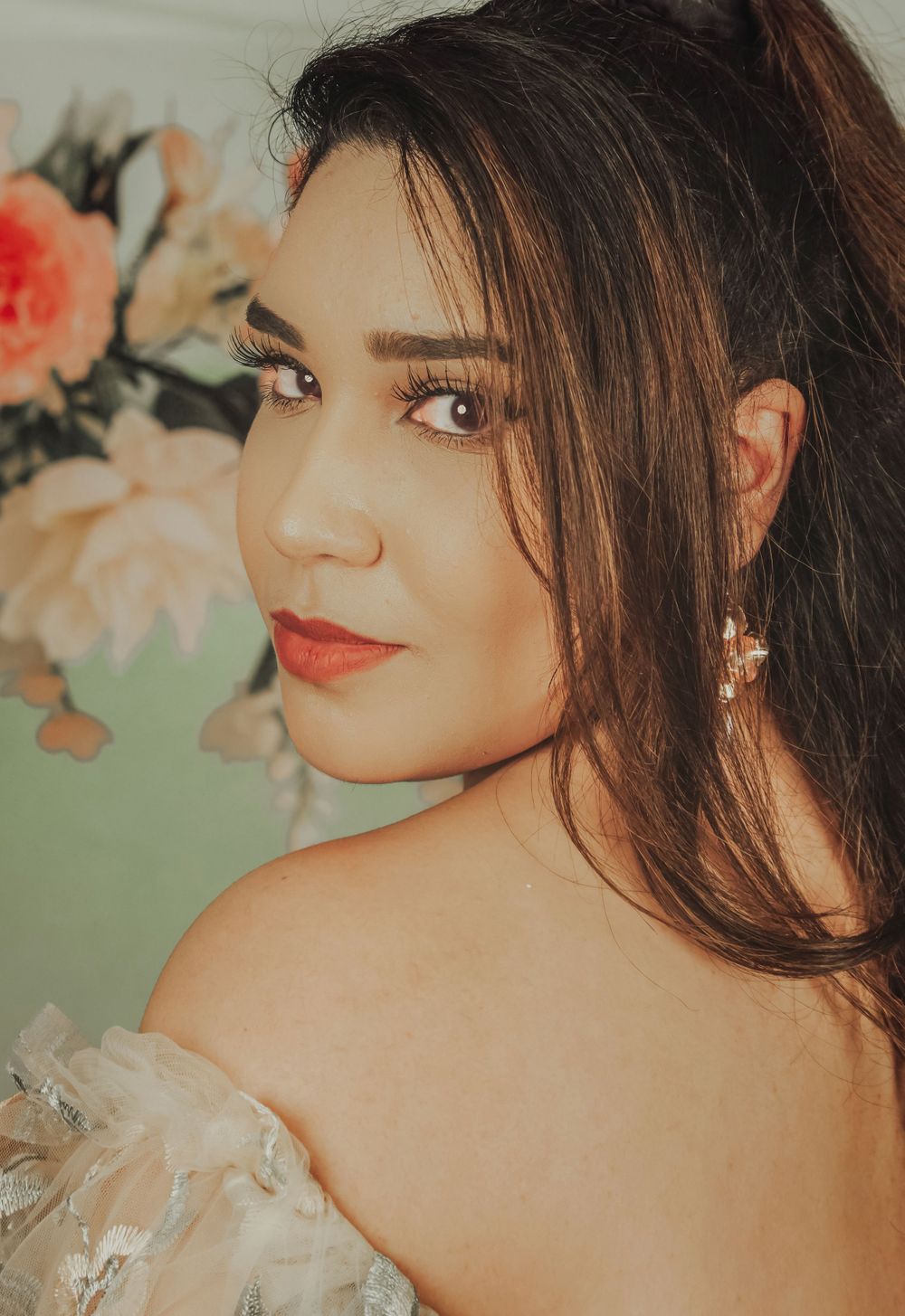 Romantic portrait with soft lighting and peach roses in background.