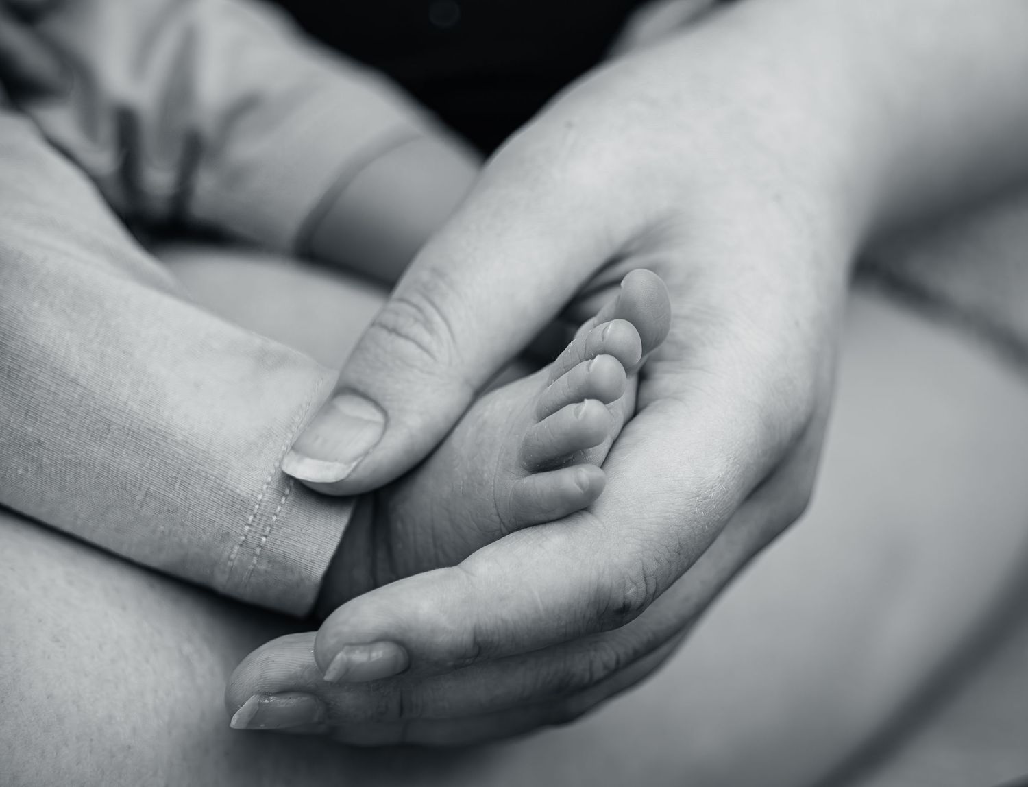 Close up photo of mum holding newborns foot