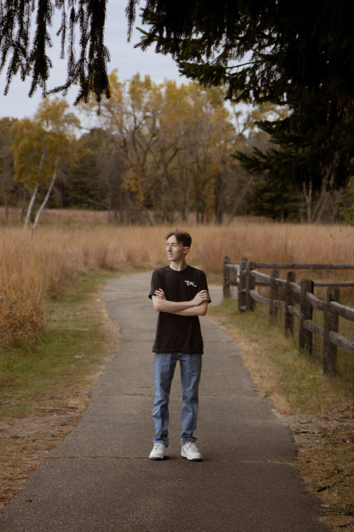 Professional portrait of someone in a beige sweater standing confidently by windows.