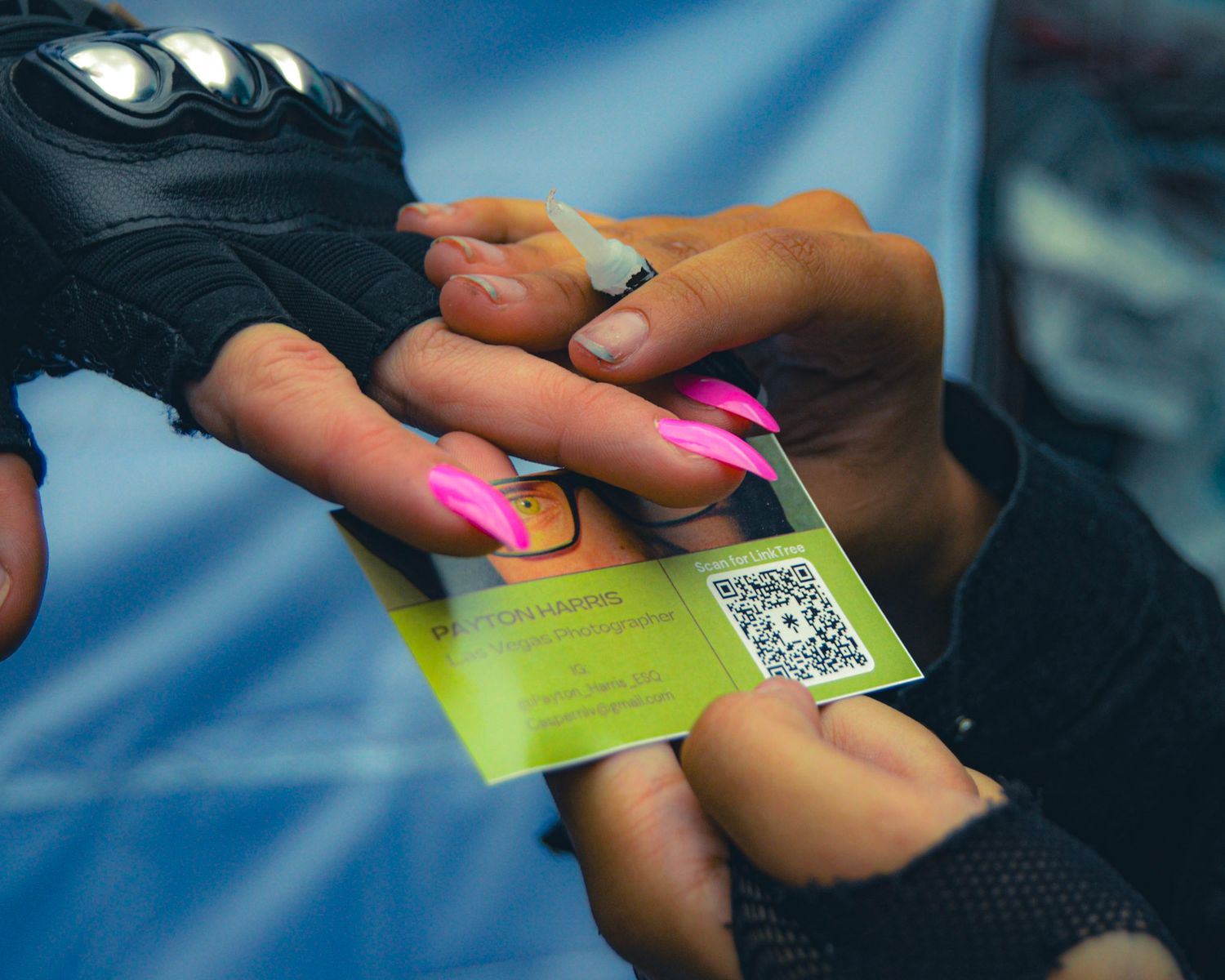 Close-up of hands holding business cards with QR codes against blue background.
