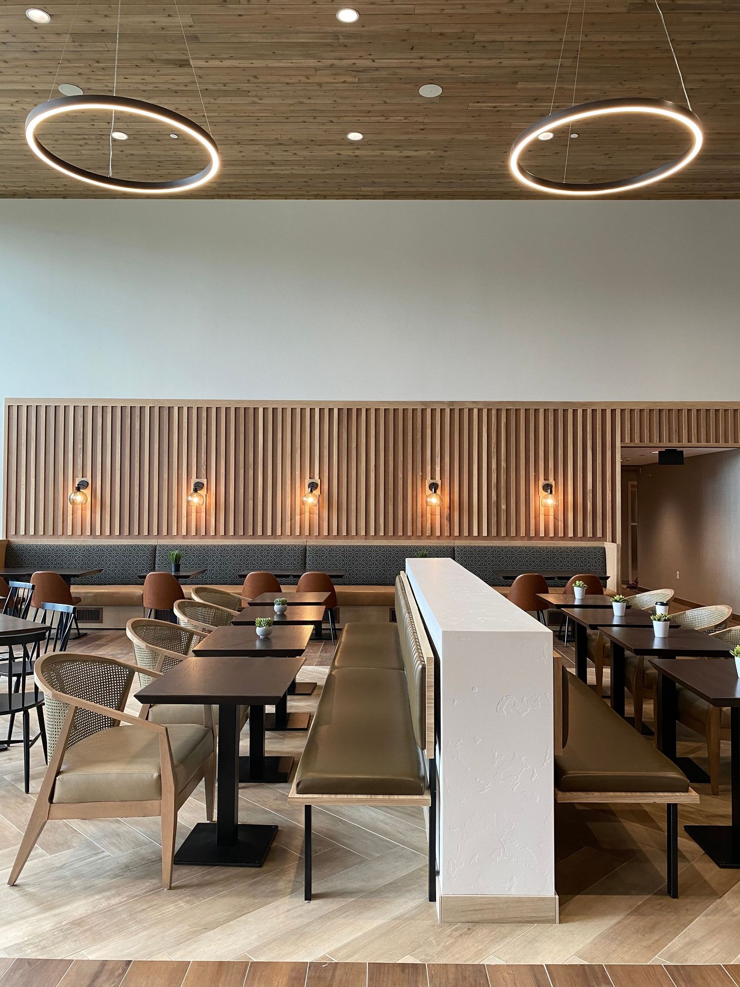 Modern restaurant interior with circular pendant lights and wood paneled walls.