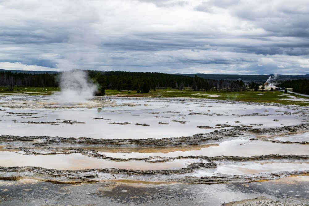 Steam rises from the geothermal features of Yellowstone's mineral-rich terraces under dramatic clouds.